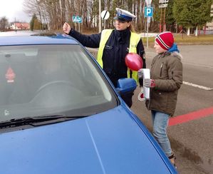 policjantka i uczeń wręczają kierowcy list i balonik