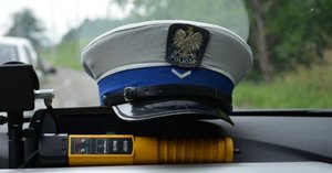 policyjna czapka na kokpicie radiowozu i urządzenie alco blow do badania stanu trzeźwości