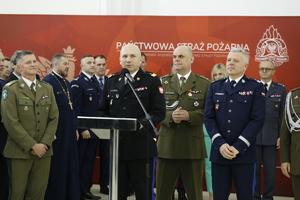 Zdjęcie przedstawia spotkanie przedświąteczne służb mundurowych. W pierwszym planie zdjęcia widzimy przemawiającego do zgromadzonych gości Komendanta Państwowej Straży Pożarnej w Lublinie nadbrygadiera Grzegorza Alinowskiego.