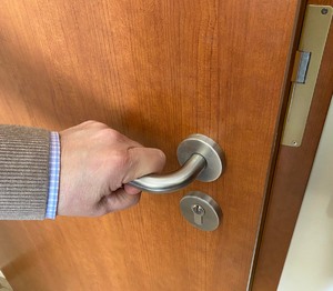 zdjęcie przedstawia rękę, która otwiera drzwi