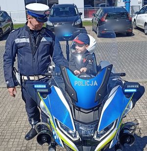 policjant stoi przy motocyklu, na którym siedzi dziecko