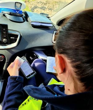 policjantka w radiowozie sprawdza dokumenty kierowcy
