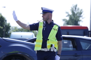 Policjant reguluje ruchem aut  na skrzyżowaniu.