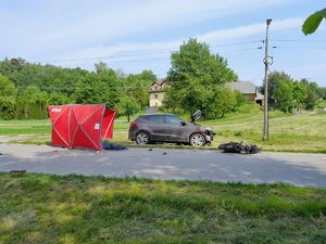 zdjęcie z miejsca zdarzenia. Na zdjęciu widać uszkodzony pojazd marki Hyundai oraz motorower, który leży obok. Obok pojazdu ustawiony jest parawan.