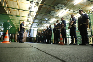 Zdjęcie przedstawia policjantów na strzelnicy w czasie omawiania zasad bezpieczeństwa podczas strzelania.