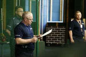 Zdjęcie przedstawia trzech policjantów na strzelnicy. Funkcjonariusze omawiają zasady konkursu podczas zawodów.