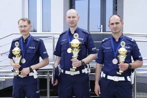 Na zdjęciu stoi trzech policjantów z pucharami i medalami. Od lewej mł. asp. Piotrem Konopko, mł. asp. Piotrem Konopko, st.sierż. Damian Lewczuk.