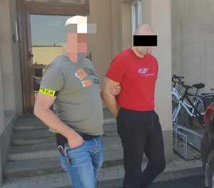 zatrzymany mężczyzna doprowadzany przez policjanta