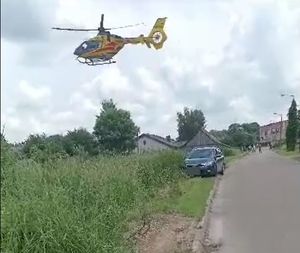 helikopter unooszący się. W tle pojazd osobowy na drodze