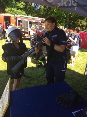policjantka pomaga dziecku przymierzyć elementy wyposażenia