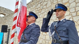 Policjanci oddają honor podczas odgrywanego hymnu Polski.