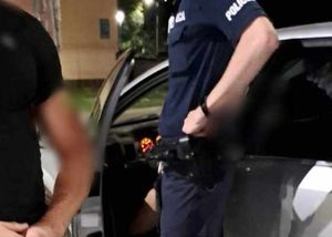 policjant stoi przy pojeździe, w którym siedzi pijany kierowca. obok policjant po cywilnemu