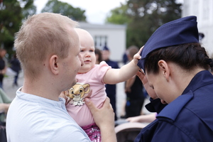Małe dziecko dotyka rączką furażerki nowej policjantki.