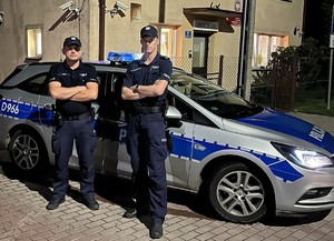 dwóch policjantów stoi przy radiowozie