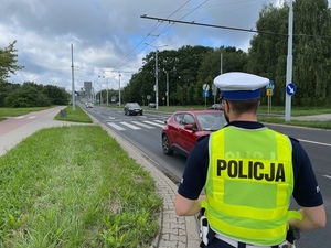 policjant z ruchu drogowego stoi przy jezdni