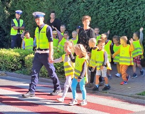 policjant prowadzi dzieci przez przejście