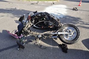 przewrócony motocykl na drodze z uszkodzeniami