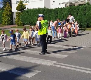 policjant z drogówki uczy dzieci przechodzenia przez przejście dla pieszych