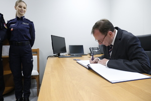 Minister Spraw Wewnętrznych i Administracji Mariusz  Kamiński wpisuje się do księgi pamiątkowej.