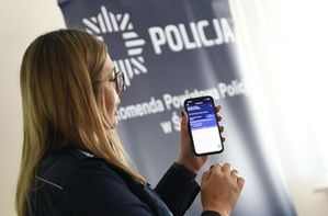 policjantka pokazuje aplikacje na smartfonie