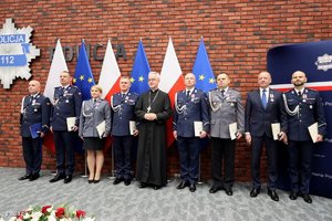 Odznaczeni medalami stoją na tle 6 flag. 3 Polski i 3 Unii Europejskiej