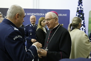 Metropolita Lubelski Jego Ekscelencja ks. Abp. Stanisław Budzik dzieli się opłatkiem z policjantem.