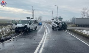 miejsce zdarzenia drogowego w miejscowości Jarosławiec, na drodze stoją dwa uszkodzone pojazdy - bus marki Renault i samochód osobowy marki Citroen, w tle widać radiowóz nieoznakowany z włączonymi sygnałami błyskowymi