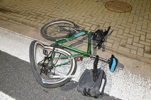 uszkodzony rower leżący częściowo na jezdni