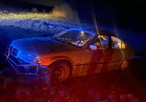 stojący na łące uszkodzony samochód marki BMW