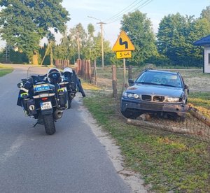 policyjny motocykl a obok drogi rozbite auto