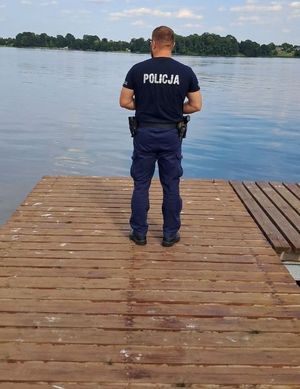 policjant stoi na pomoście nad wodą