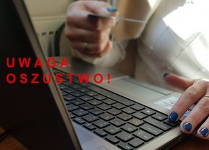 fragment zdjęcia na którym jest osoba siedząca przy laptopie trzymająca w ręku kartę płatniczą. Czerwony napis uwaga oszustwo