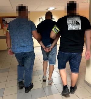 policjanci prowadzą zatrzymanego mężczyznę