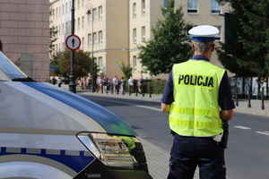 Policjant stoi przy radiowozie.