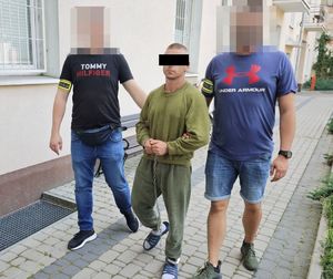 policjanci po cywilnego  prowadzą zatrzymanego w kajdankach