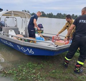 policjanci na łodzi rozwożą żywność wraz ze strażakami