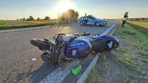 miejsce wypadku, motocykl leżący na jezdni, w tle radiowóz