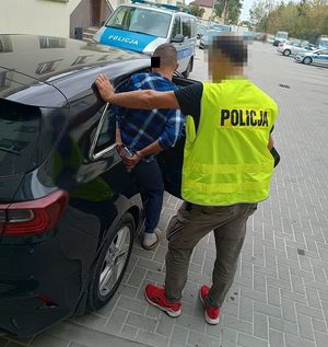 zatrzymany mężczyzna przy samochodzie, obok policjant