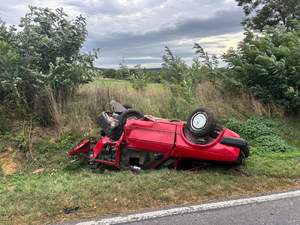 przewrócony pojazd koloru czerwonego, leży na dachu