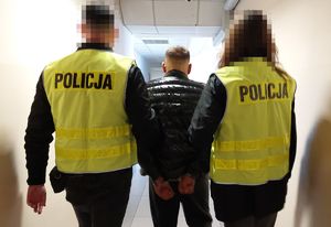 Policjanci prowadzą zatrzymanego mężczyznę