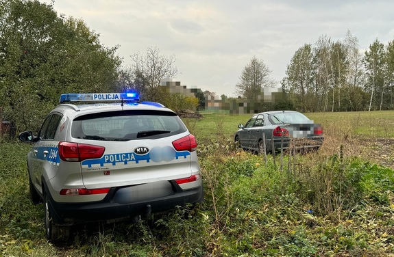 radiowóz i samochód marki Mitsubishi na polu