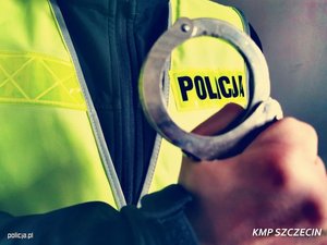 kajdanki trzymane w ręce i napis Policja