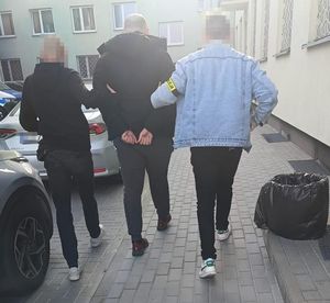 policjanci prowadzą zatrzymanego mężczyznę