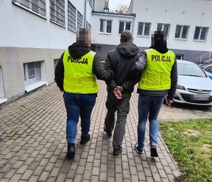 Policjanci prowadzą zatrzymanego mężczyznę