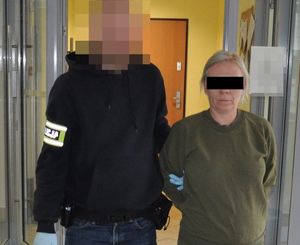 policjant prowadzi zatrzymaną kobietę