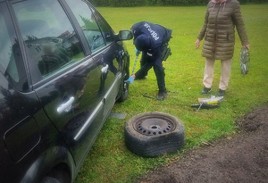 policjant zmienia koło w pojeździe seniorki