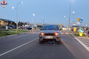 stojący na jezdni Jeep, na trawie na poboczu leży rower