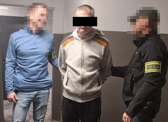 mężczyzna z zasłoniętymi oczami, prowadzą go policjanci