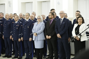 Na zdjęciu znajdują się policjanci stojący w szeregu oraz goście zaproszeni na spotkanie opłatkowe.