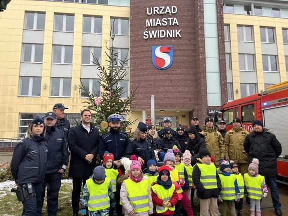 Zdjęcie grupowe dzieci, policjantów, strażaków i pracowników urzędu przed budynkiem Urzędu Miasta Świdnik